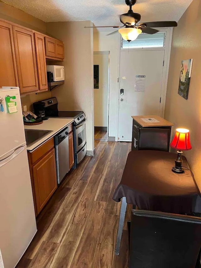 kitchen featuring ceiling fan, a textured ceiling, sink, white appliances, and dark wood-type flooring