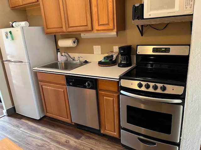 kitchen with appliances with stainless steel finishes, sink, and dark hardwood / wood-style flooring