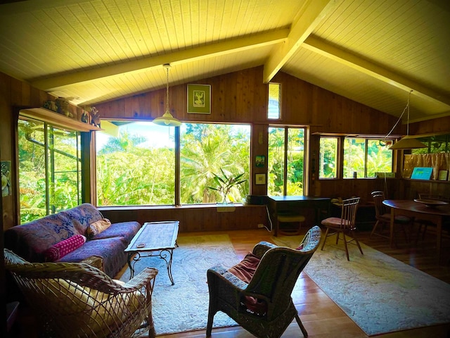 living room featuring wood-type flooring, vaulted ceiling with beams, a wealth of natural light, and wood walls