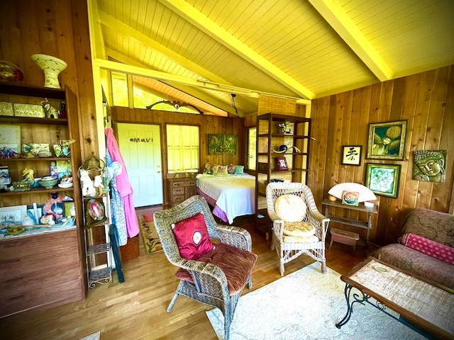 interior space with lofted ceiling with beams, wooden walls, and light hardwood / wood-style floors