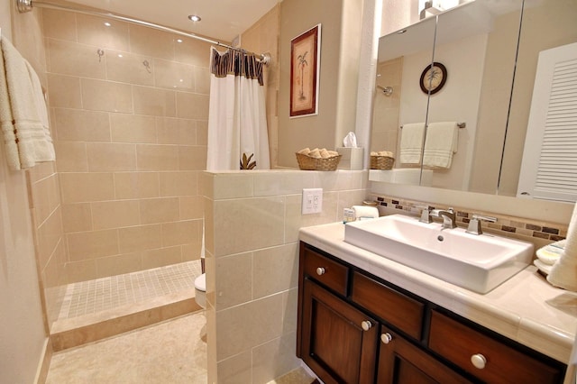 bathroom featuring a shower with shower curtain, decorative backsplash, vanity, tile walls, and toilet