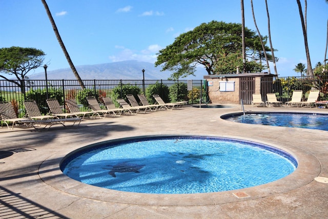 view of pool featuring a mountain view, a patio, and a hot tub