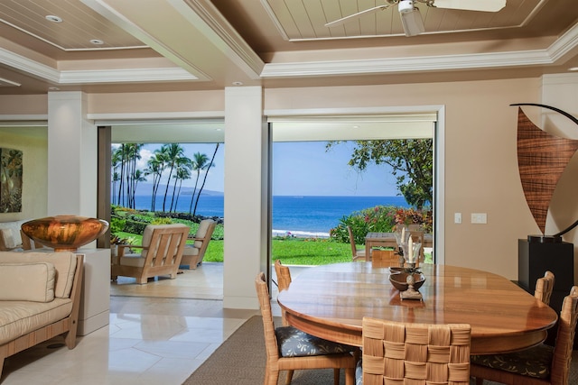 dining space featuring a tray ceiling, light tile patterned floors, a water view, ornamental molding, and a ceiling fan