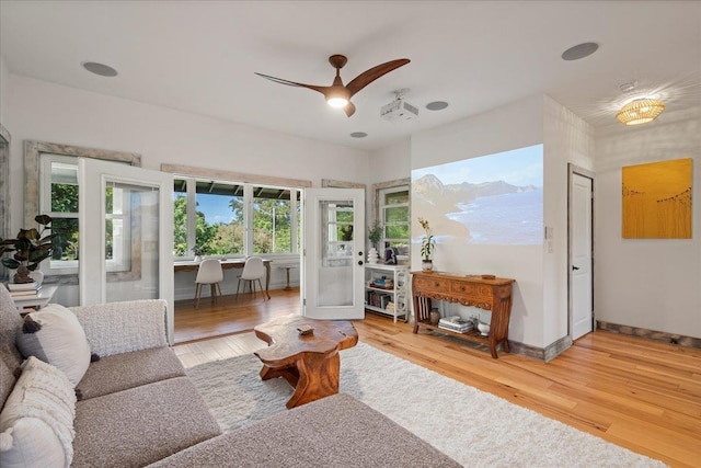 living area with light wood-style floors, baseboards, and a ceiling fan