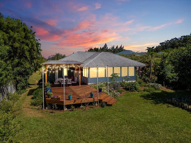 back of property featuring roof with shingles, a lawn, and a wooden deck