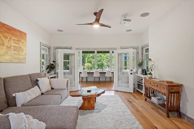 living room featuring light wood-style flooring, ceiling fan, and french doors