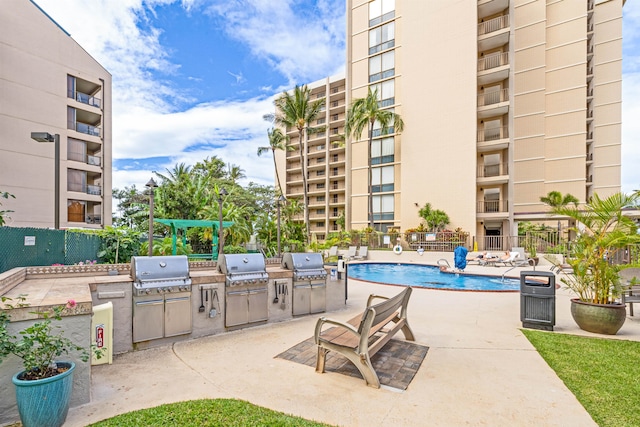 view of patio with a grill, a community pool, and exterior kitchen