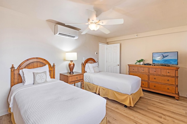 bedroom with light hardwood / wood-style floors, a wall unit AC, and ceiling fan