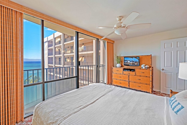 bedroom with access to exterior, ceiling fan, and a water view