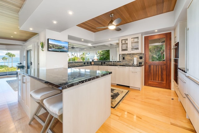 kitchen featuring a wealth of natural light, ceiling fan, backsplash, and wood ceiling