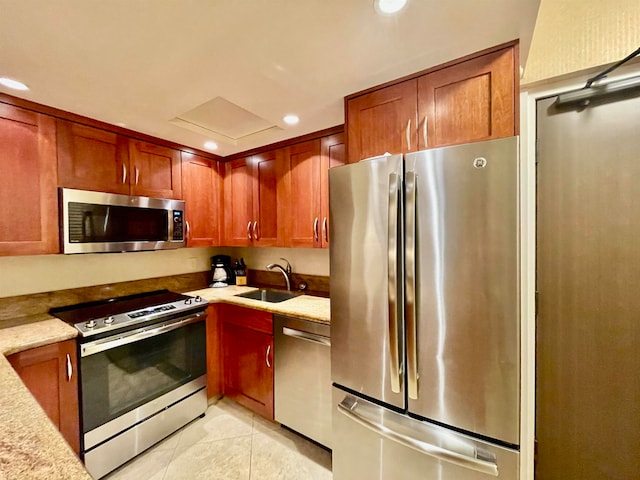 kitchen with appliances with stainless steel finishes, light tile patterned floors, light stone counters, and sink