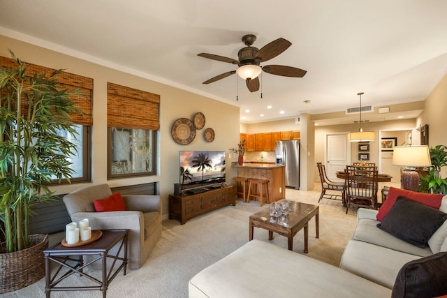 living room featuring ceiling fan, light carpet, and crown molding