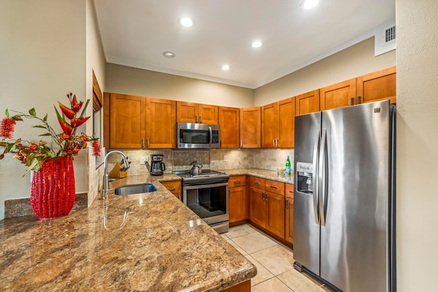 kitchen featuring light stone counters, sink, kitchen peninsula, stainless steel appliances, and backsplash