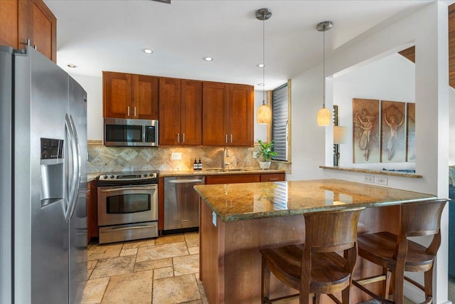 kitchen featuring kitchen peninsula, tasteful backsplash, stone countertops, appliances with stainless steel finishes, and a kitchen breakfast bar