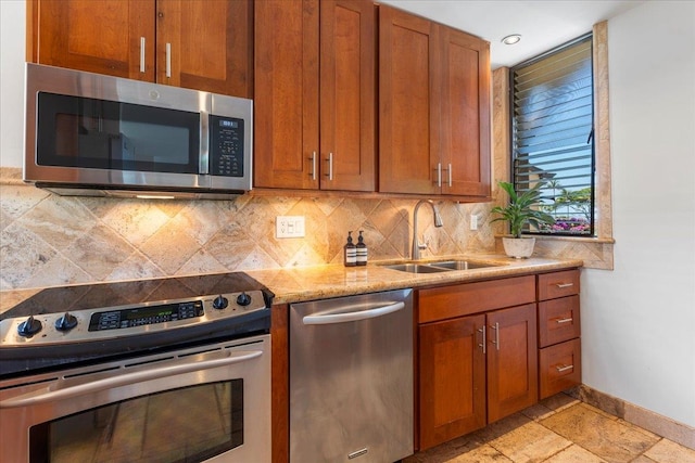 kitchen with light stone countertops, stainless steel appliances, backsplash, and sink