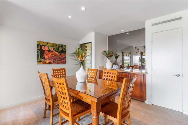 carpeted dining area with vaulted ceiling