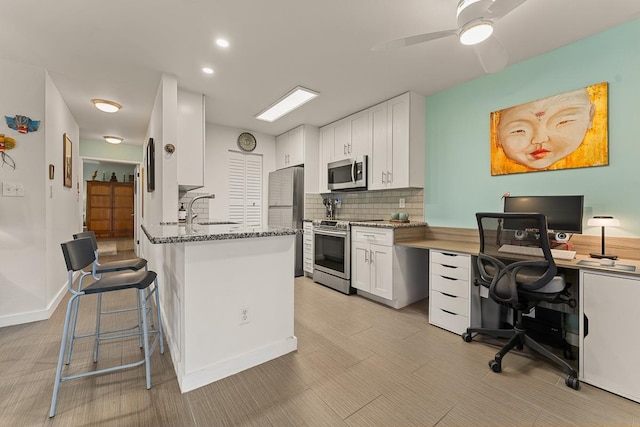 kitchen featuring ceiling fan, sink, white cabinetry, appliances with stainless steel finishes, and dark stone counters