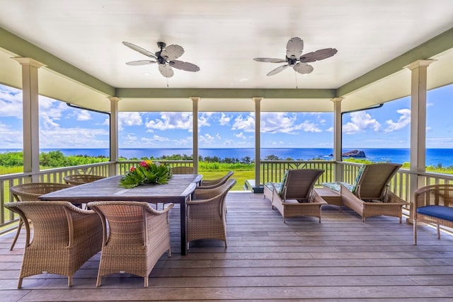 sunroom featuring ceiling fan, ornate columns, and a water view