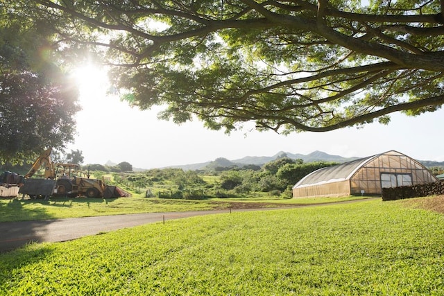 view of yard with a mountain view, an outbuilding, and a rural view