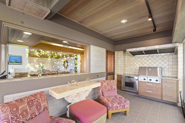 kitchen with backsplash, oven, rail lighting, light tile patterned flooring, and extractor fan