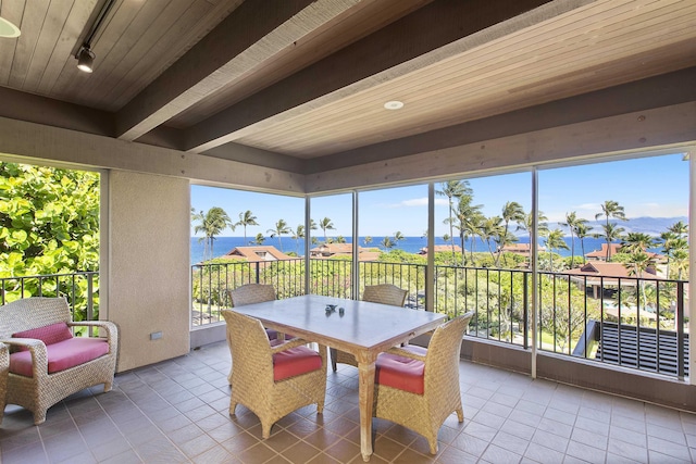 sunroom with beamed ceiling, a water view, and track lighting