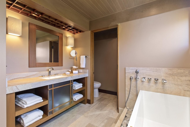 bathroom featuring a tub to relax in, vanity, and toilet