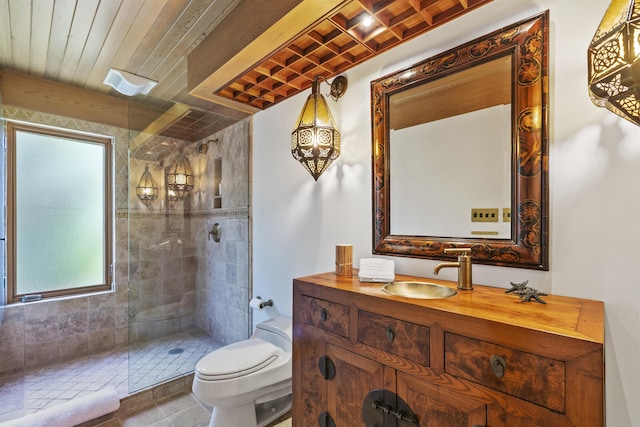 bathroom with tiled shower, tile patterned flooring, vanity, and toilet