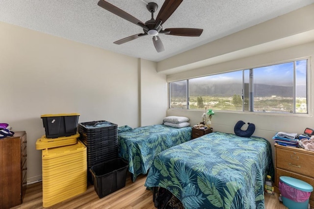 bedroom with ceiling fan, light wood-type flooring, and a textured ceiling