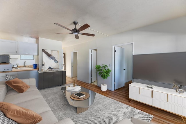 living room with dark wood-type flooring, ceiling fan, and sink