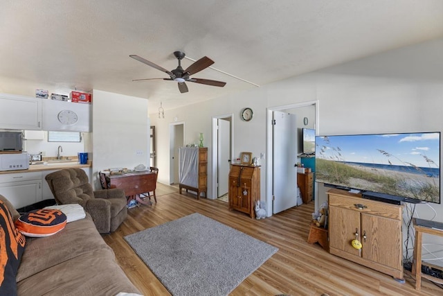 living room with ceiling fan, sink, and light hardwood / wood-style flooring