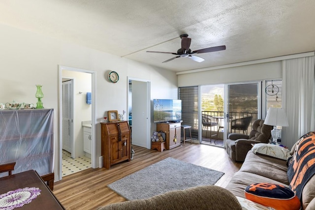 living room with ceiling fan, a textured ceiling, and light hardwood / wood-style flooring