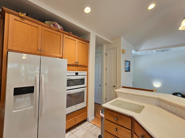 kitchen featuring light hardwood / wood-style flooring, stainless steel double oven, and white fridge with ice dispenser