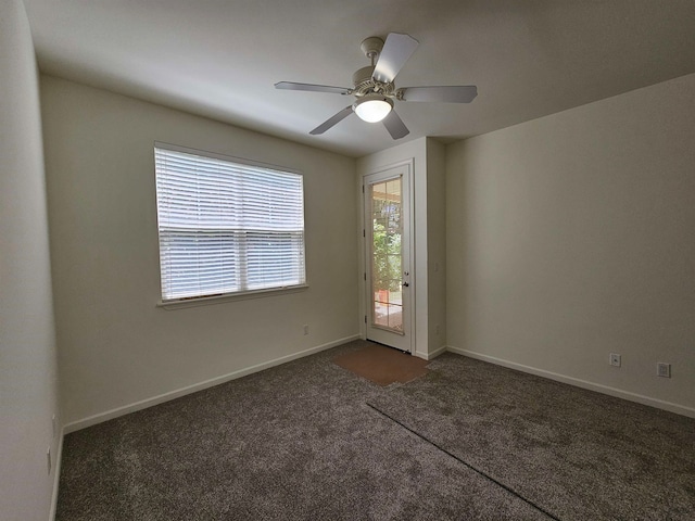 empty room with ceiling fan and dark colored carpet