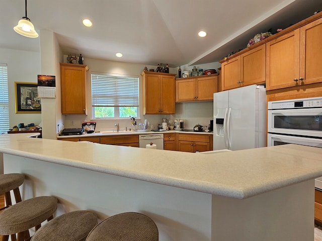 kitchen featuring white appliances, decorative light fixtures, a kitchen breakfast bar, a kitchen island, and lofted ceiling