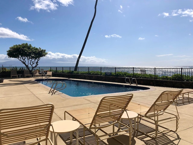 view of swimming pool with a patio area and a water view