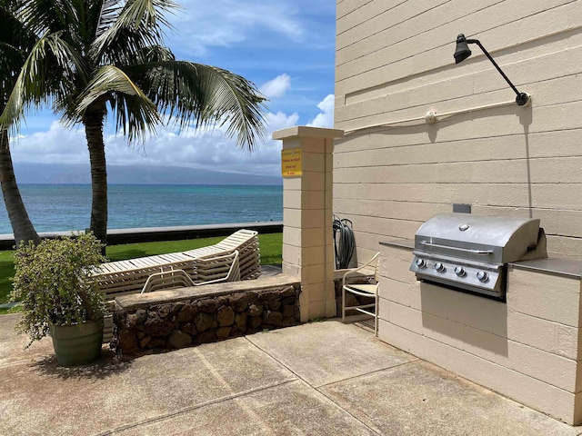 view of patio with area for grilling, a water view, and grilling area