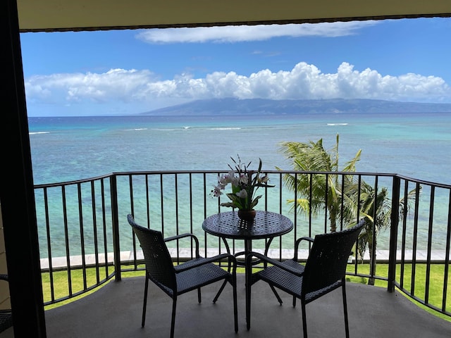 balcony with a water view and a view of the beach