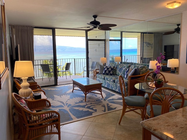 living room featuring a wall of windows, a water view, ceiling fan, and light tile patterned flooring