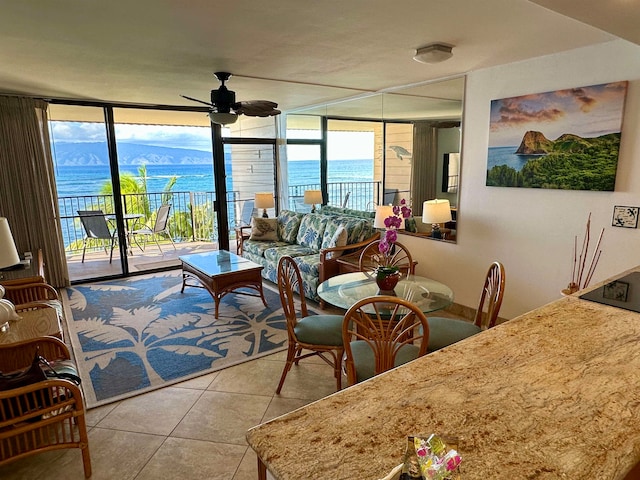 tiled living room featuring a wealth of natural light, ceiling fan, a water and mountain view, and floor to ceiling windows