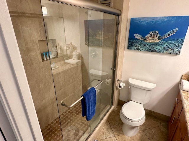 bathroom featuring tile patterned flooring, vanity, toilet, and a shower with door