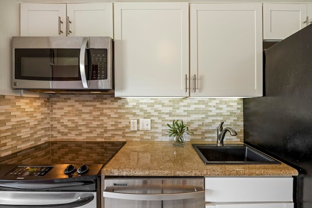 kitchen featuring white cabinets, stainless steel appliances, and light stone countertops