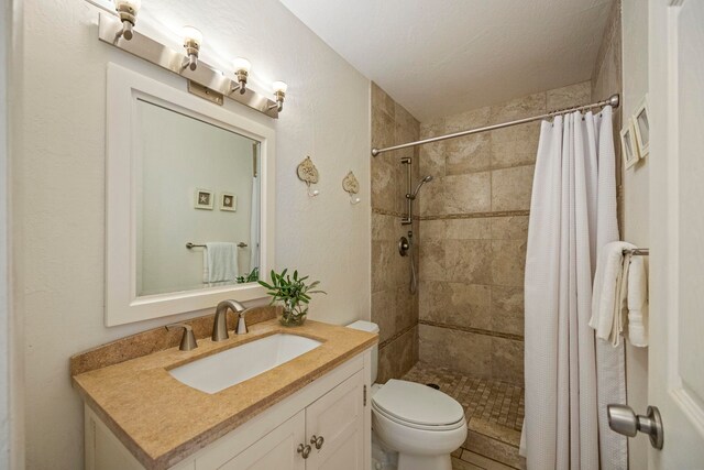 bathroom with curtained shower, vanity, a textured ceiling, and toilet