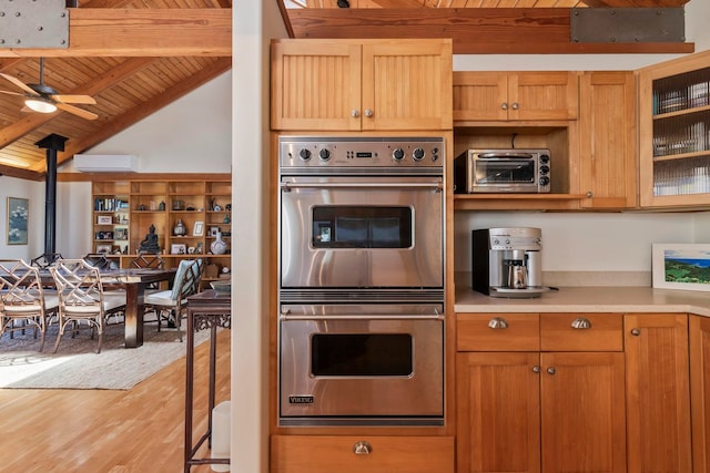 kitchen featuring wood ceiling, ceiling fan, light wood-type flooring, lofted ceiling with beams, and stainless steel double oven