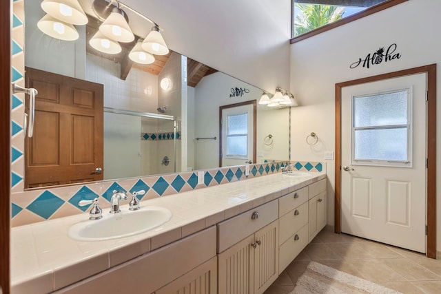 bathroom featuring lofted ceiling, decorative backsplash, a shower with door, vanity, and tile patterned flooring