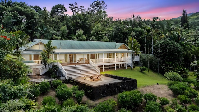 back house at dusk with a deck and a lawn