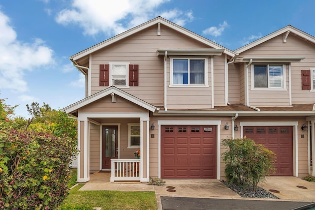 townhome / multi-family property with concrete driveway, covered porch, and an attached garage