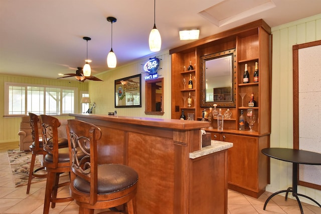 bar with light tile patterned floors, hanging light fixtures, bar, and a ceiling fan