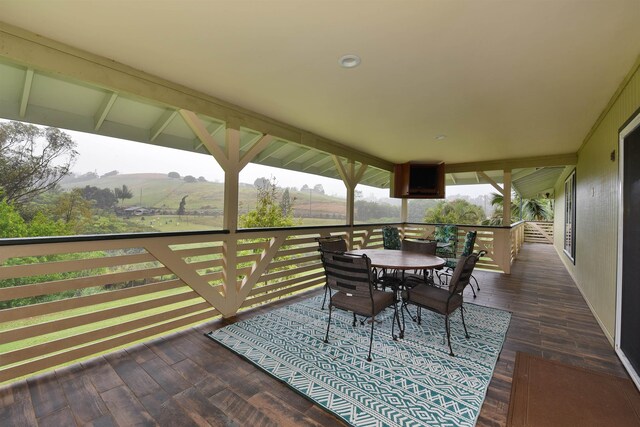 deck with outdoor dining area and a rural view