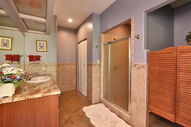 bathroom featuring a shower stall, vanity, wainscoting, tile patterned floors, and tile walls