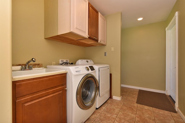 washroom featuring a sink, cabinet space, light tile patterned floors, baseboards, and washing machine and clothes dryer